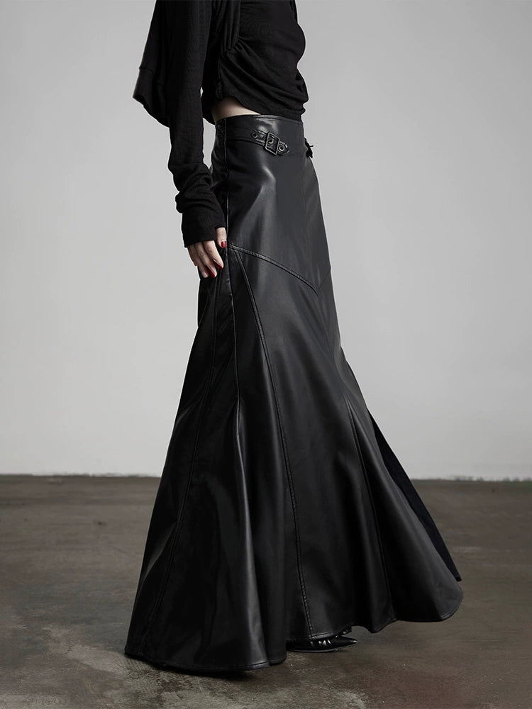 A person standing in a neutral pose wearing a long black leather skirt with a slit.