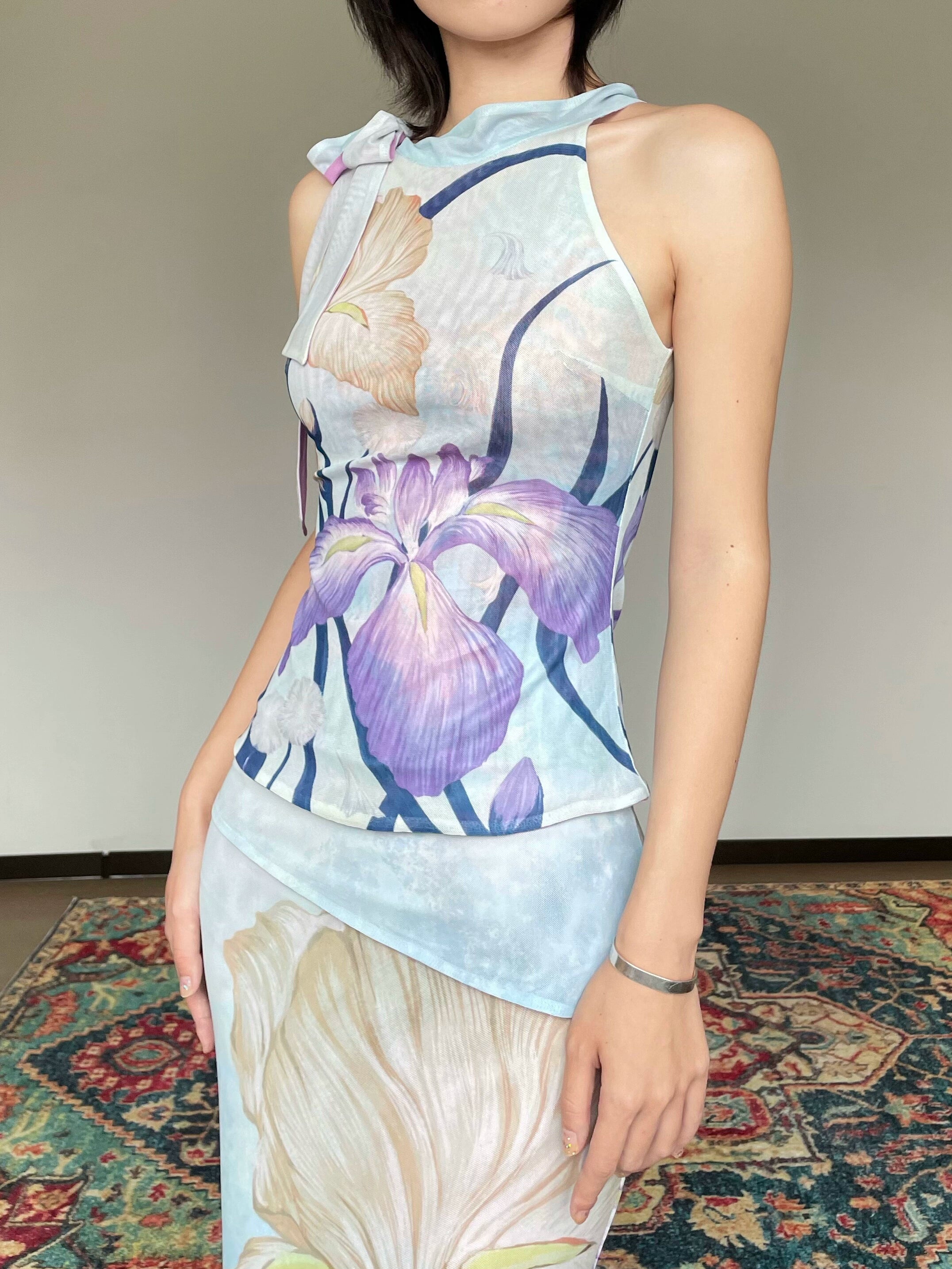 Person wearing a sleeveless top with floral design on a patterned rug