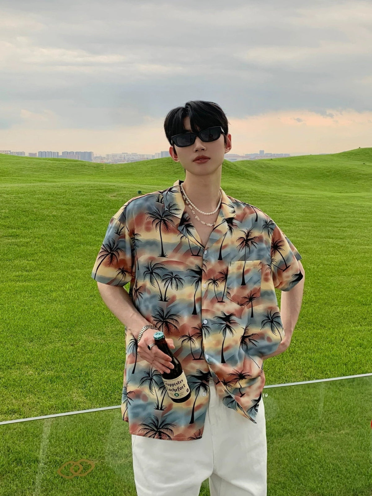 Person wearing a colorful shirt with palm tree pattern on a grassy field