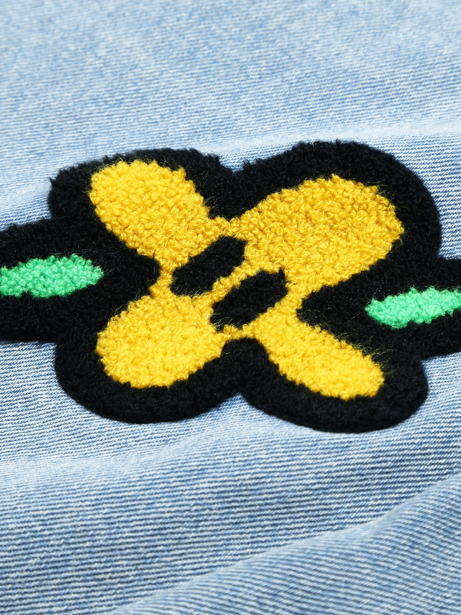 Textured flower embroidery detail on light wash denim