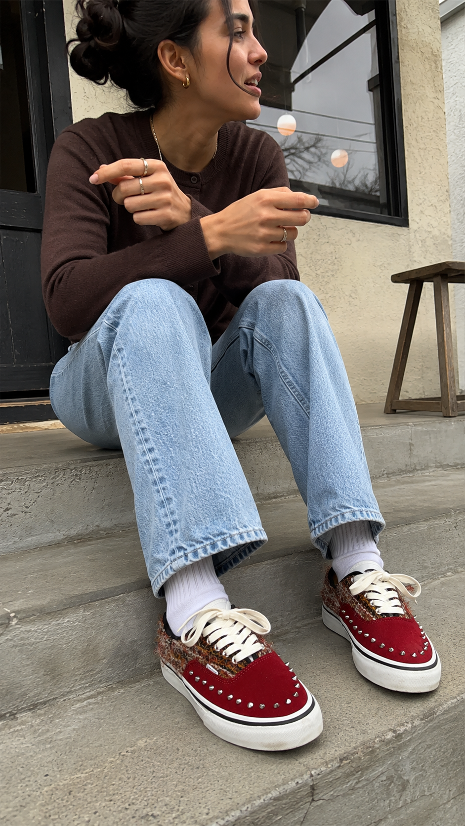 Reddish-brown studded suede low-top sneakers worn on cafe steps